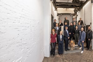 Die Mitarbeitenden von Second Elements posieren in einem modernen Hamburger Büroflur mit Backsteinwänden